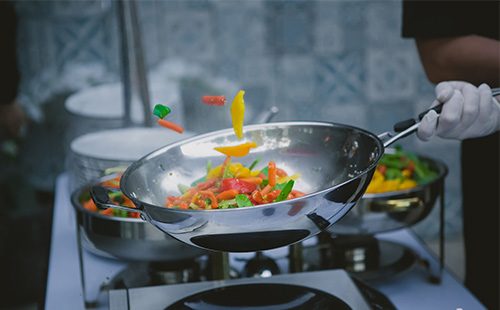 В сковороде вок жарятся овощи